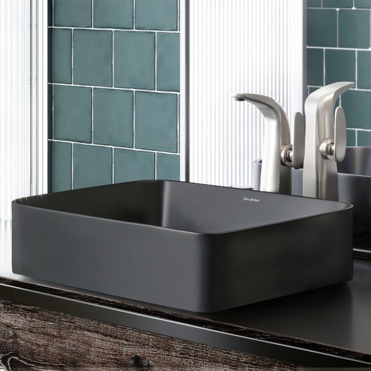 Rectangular matte black ceramic vessel sink with flat edges on a dark countertop.