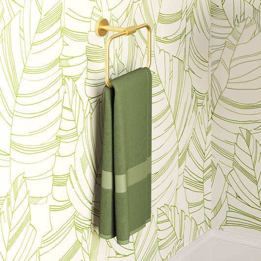 Avallon towel ring in brushed gold finish holding a folded green towel with a striped pattern.