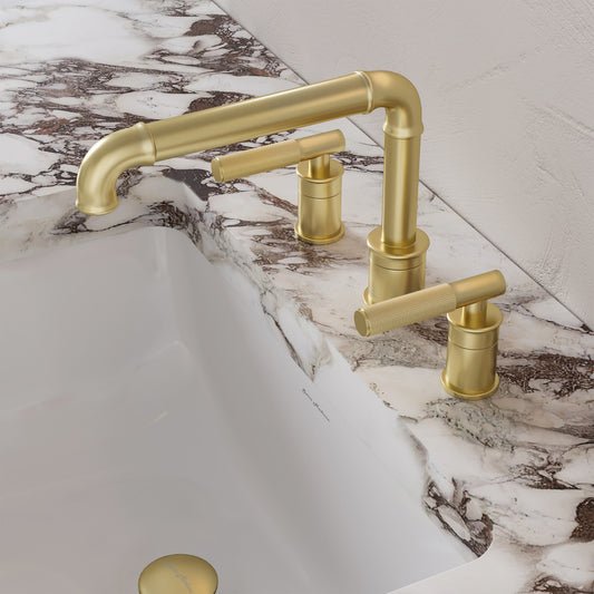 Widespread bathroom faucet in brushed gold with sleek handles and high-arc spout on marble countertop.